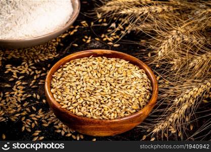 Bowls with wheat and flour grains. On a black background. . Bowls with wheat and flour grains.
