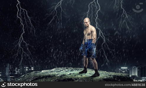 Box fighter trainning outdoor. Strong boxer on dark background demonstrating power and endurance