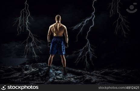 Box fighter trainning outdoor. Strong boxer on dark background demonstrating power and endurance