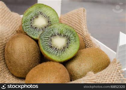 Box of fresh kiwi in on wooden background