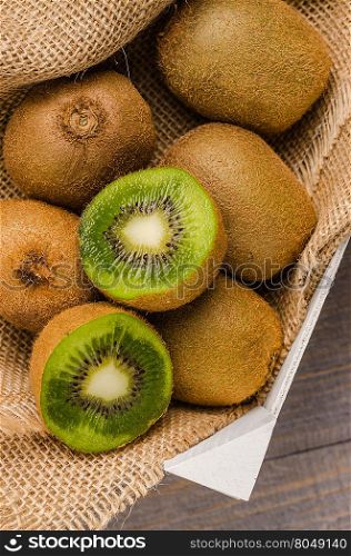 Box of fresh kiwi in on wooden background. Top view with copy space
