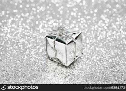 Box with christmas gift on shiny silver background
