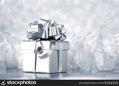 Box with christmas gift on shiny silver background