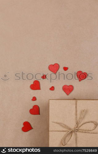 Box with gifts wrapped in brown craft paper and red paper hearts Valentines day concept. Gift and red hearts