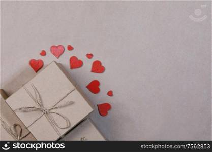 Box with gifts wrapped in brown craft paper and red paper hearts Valentines day concept. Gift and red hearts