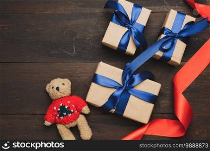  box wrapped in brown kraft paper and tied with red silk ribbon on brown wooden background, top view
