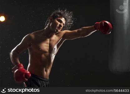 Boxer hitting punching bag over black background