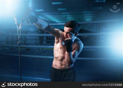 Boxer in bandages training with bag in gym. Boxing workout, mens sport. Boxer in bandages training with bag in gym