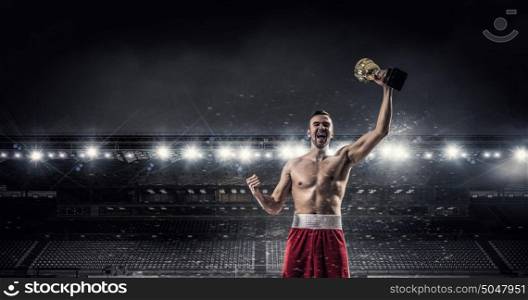 Boxer man celebrate victory. Boxer man at arena raising hand with golden cup