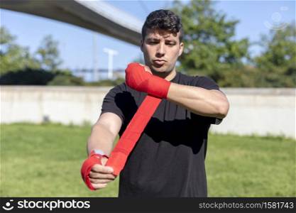 Boxer preparing for training with forearm bandage outdoors