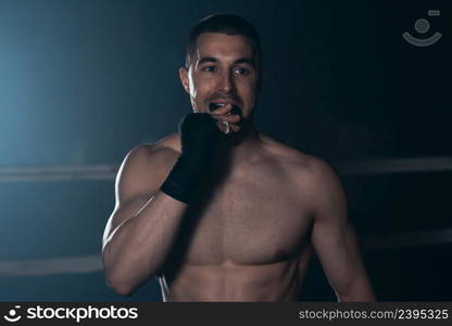 Boxer puts Teeth mouth protection in combat sport. Boxer uses mouth guard before fight. High quality photography.. Boxer puts Teeth mouth protection in combat sport. Boxer uses mouth guard before fight.