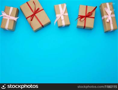 boxes wrapped in brown paper and tied with a red bow, gifts on a blue background, place for text