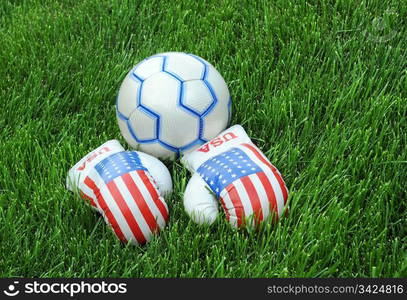 Boxing gloves with US flag image and soccer ball on the green lawn