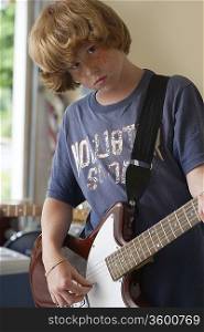 Boy (10-12) playing electric guitar in garage portrait