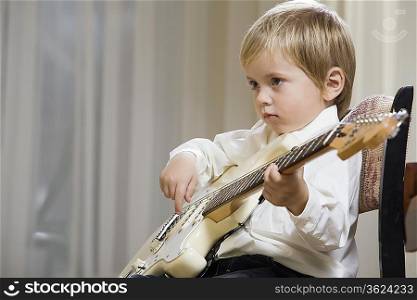 Boy (3-4) playing guitar