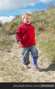Boy (3-4) walking on sand dunes