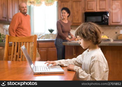 Boy (4-5) using laptop while parents standing in background