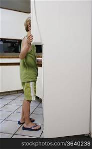 Boy (5-6) looking into fridge