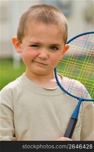 Boy (6-7) holding racket, portrait