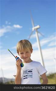 Boy (7-9) holding toy walky-talky at wind farm, portrait