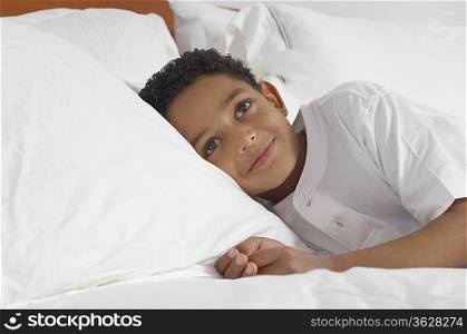 Boy (7-9) lying in bed smiling, portrait