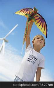 Boy (7-9) playing with kite at wind farm