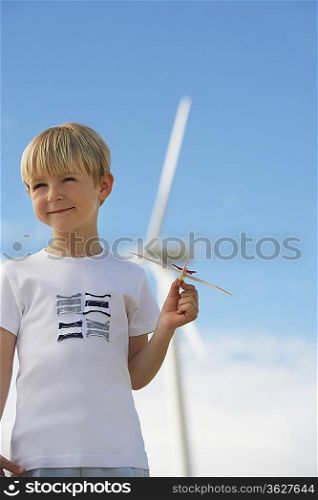 Boy (7-9) playing with toy glider at wind farm