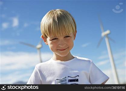 Boy (7-9) smiling at wind farm, portrait