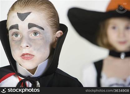 Boy (7-9) wearing dracula costume girl in background