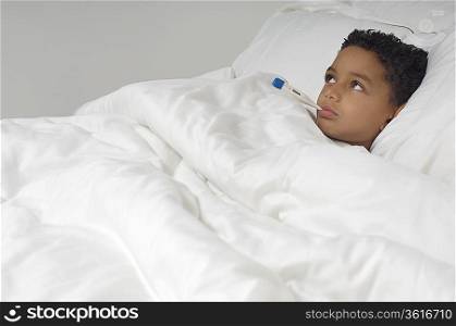 Boy (7-9) with thermometer in mouth, lying in bed