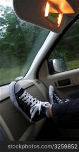Boy&acute;s feet on dash of moving car.