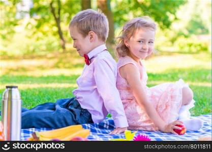 boy and a girl of 6 years on a picnic sitting back to back