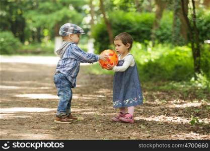 Boy and girl are playing with ball outdoor. Boy and girl