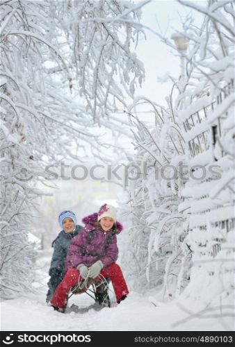 Boy And Girl at sledging Through Snowy in a fairytale landscape