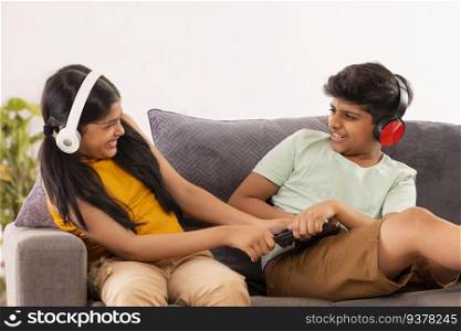 Boy and girl fighting over digital tablet while sitting on sofa in living room
