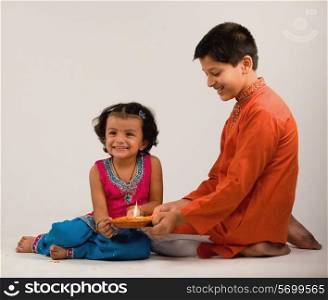 Boy and girl holding a diya together