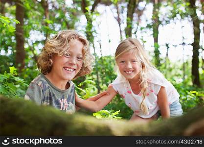 Boy and girl in forest looking at camera smiling