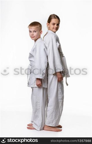 Boy and girl in sports kimono stand with their backs to each other