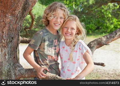 Boy and girl next to tree looking at camera smiling