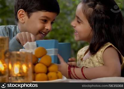Boy and girl opening gifts on Diwali