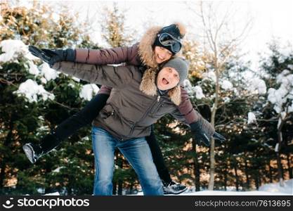 boy and girl outdoors on a winter walk playing snowballs and sledding
