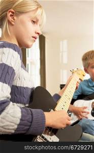 Boy and girl playing electric guitars at home