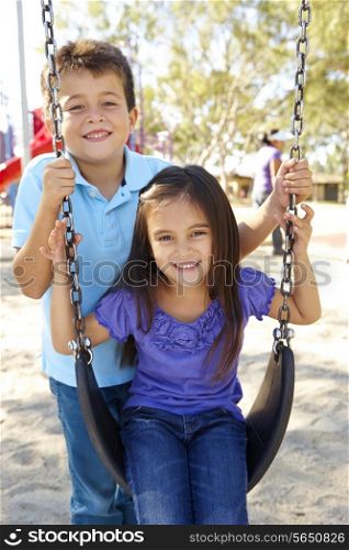 Boy And Girl Playing On Swing In Park