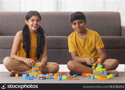 Boy and girl playing with toy blocks in living room at home