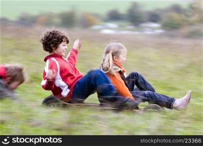 Boy and girl riding a mountain board with a boy pushing them from behind