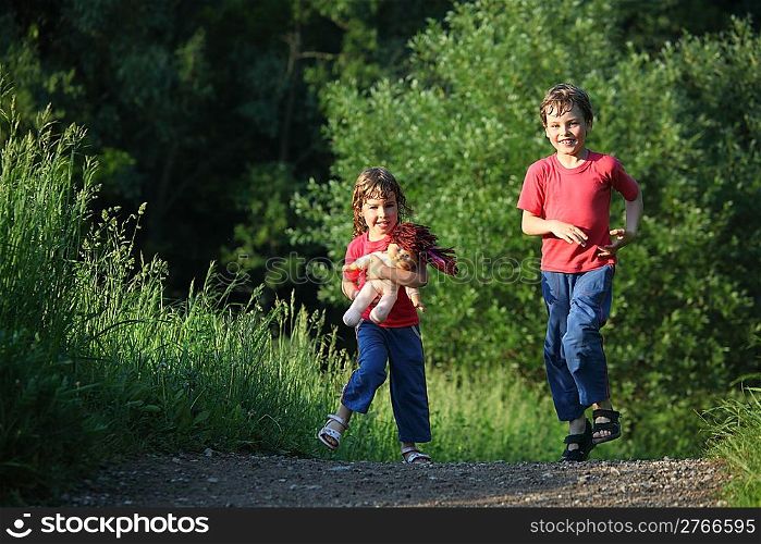 boy and girl run with doll in park