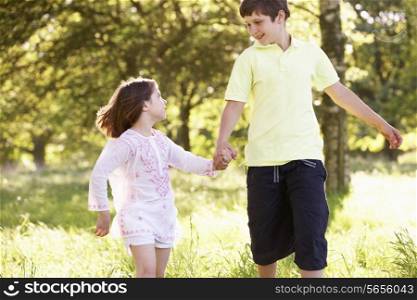 Boy And Girl Running Through Summer Field Together