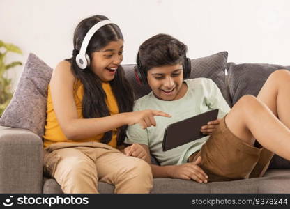 Boy and girl using digital tablet and listening music on headphones