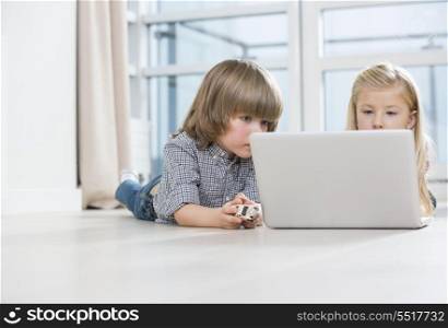 Boy and girl using laptop on floor at home