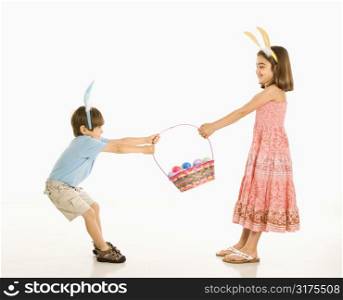 Boy and girl wearing bunny ears fighting over Easter basket.